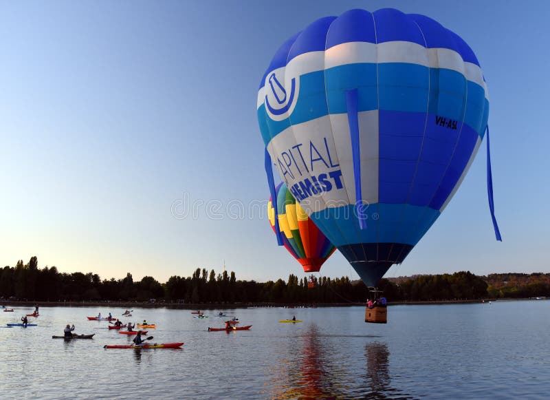 Kayakers που προσέχει τα μεγάλα ζωηρόχρωμα μπαλόνια ζεστού αέρα στοκ φωτογραφία με δικαίωμα ελεύθερης χρήσης Kayakers που προσέχει τα μεγάλα ζωηρόχρωμα μπαλόνια ζεστού αέρα στοκ φωτογραφία με δικαίωμα ελεύθερης χρήσης