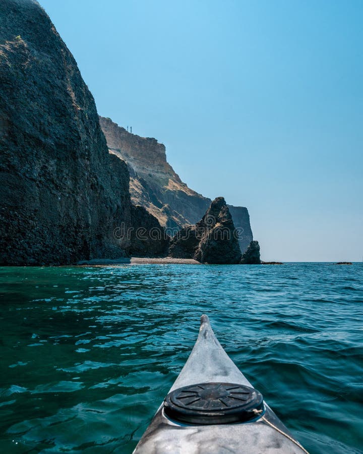 Kayaking along the coast of the island near the rocks. Canoeing adventure on a calm sea with blue water stock photography Kayaking along the coast of the island near the rocks. Canoeing adventure on a calm sea with blue water stock photography
