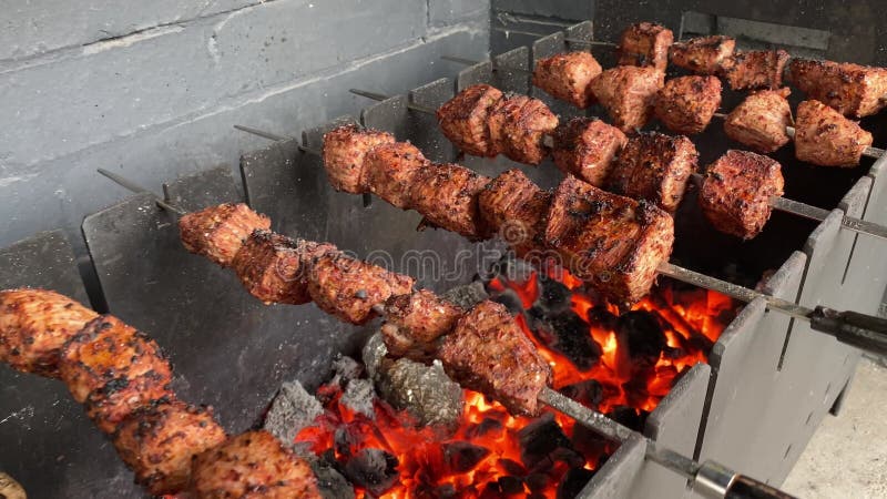 Muitos kebabs seguidos na grelha. espetadas amarradas em espetos de madeira  em um café de rua. o processo de cozinhar kebabs com muita fumaça.