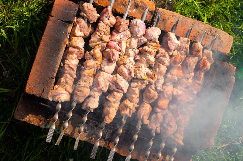 Kebab wieprzowy na skewersach jest smażony na ceglanym grillu. piknik zewnętrzny.