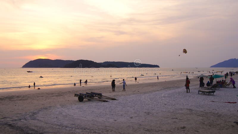 KEDAH, LANGKAWI, MALÁSIA - 8 de abril de 2015: Turistas que têm o momento romântico durante o por do sol na praia de Cenang imagens de stock KEDAH, LANGKAWI, MALÁSIA - 8 de abril de 2015: Turistas que têm o momento romântico durante o por do sol na praia de Cenang imagens de stock