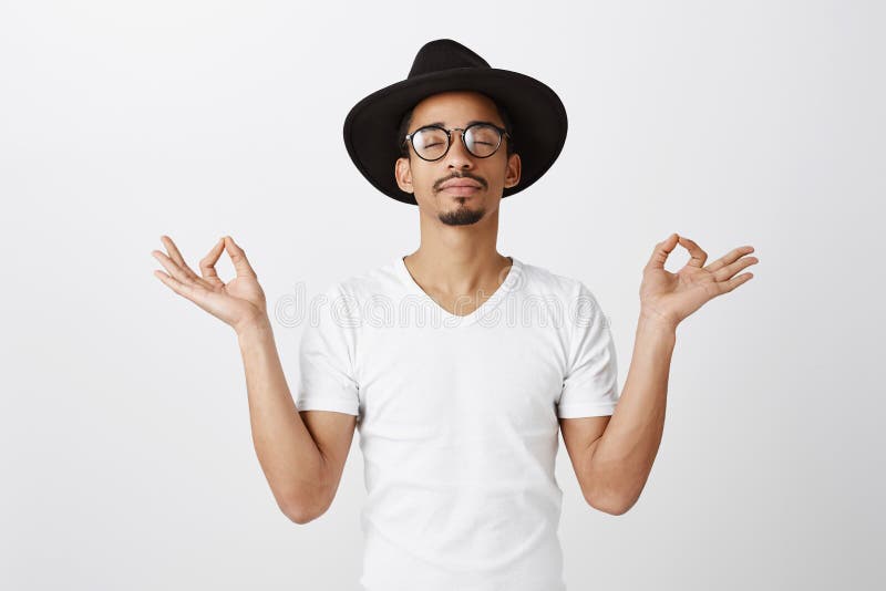 Keep calm and carry on. Studio portrait of relaxed handsome african-american fashion designer in stylish glasses and hat stock image Keep calm and carry on. Studio portrait of relaxed handsome african-american fashion designer in stylish glasses and hat stock image