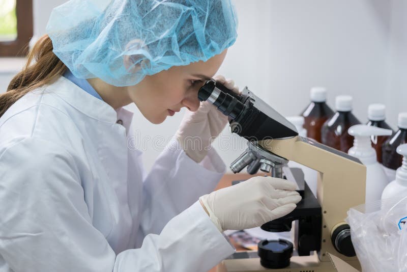 Kemist som analyserar prövkopian under mikroskopet i laboratorium av cosme royaltyfri bild