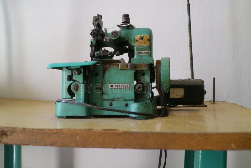 A Green Overlock Machine for Sewing Clothes is Placed on the Table