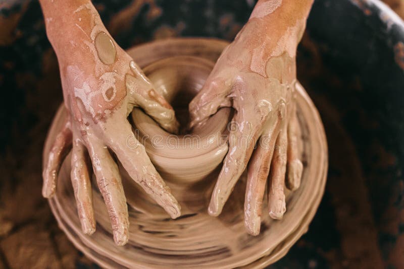 Potter making a clay pot on pottery wheel in workshop. Close up of hands of craftswoman moulding clay on pottery wheel. Potter making a clay pot on pottery wheel in workshop. Close up of hands of craftswoman moulding clay on pottery wheel.