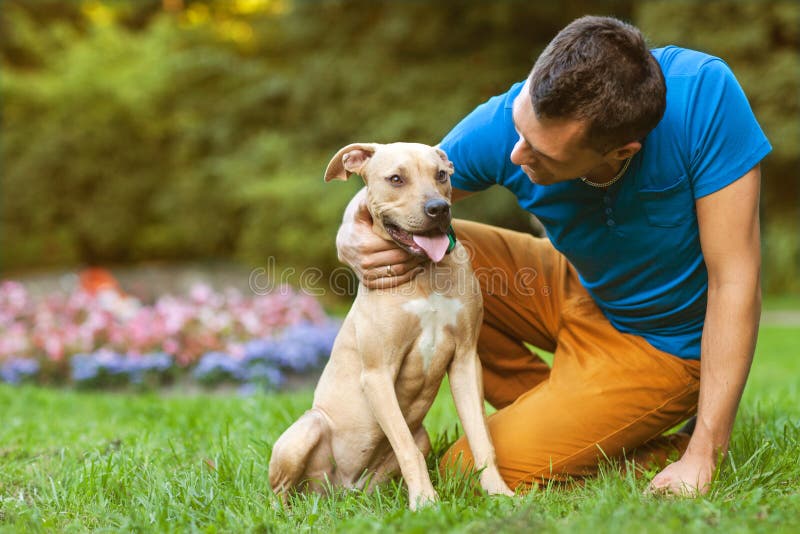 Kerl mit seinem Hund, der im Park umarmt lizenzfreie stockfotos Kerl mit seinem Hund, der im Park umarmt lizenzfreie stockfotos
