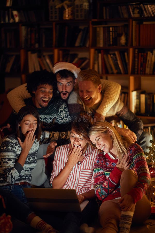Kerstfilm: jonge mensen die op kerstavond een laptop bekijken stock fotografie Kerstfilm: jonge mensen die op kerstavond een laptop bekijken stock fotografie