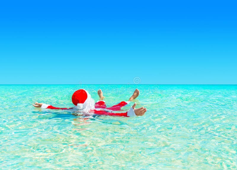 Kerstmis Santa Claus ontspant het zwemmen in oceaan turkoois transparant water