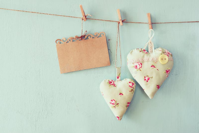 Kerstmisbeeld van stoffenharten en lege kaart voor het toevoegen van tekst het hangen op kabel voor blauwe houten achtergrond Gef stock afbeelding Kerstmisbeeld van stoffenharten en lege kaart voor het toevoegen van tekst het hangen op kabel voor blauwe houten achtergrond Gef stock afbeelding