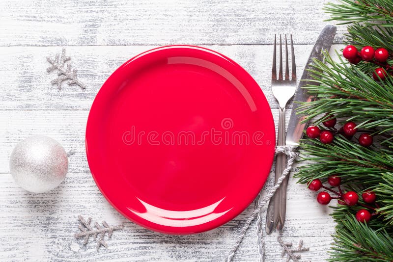 Kerstmislijst die met lege rode plaat, giftvakje en tafelzilver op lichte houten achtergrond plaatsen Sparrentak, hulstbessen royalty-vrije stock fotografie Kerstmislijst die met lege rode plaat, giftvakje en tafelzilver op lichte houten achtergrond plaatsen Sparrentak, hulstbessen royalty-vrije stock fotografie