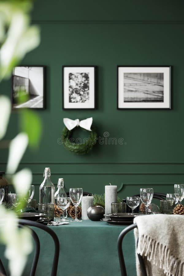 Kerstmisslinger en zwart-witte affiches op groene muur van eetkamerreeks voor Kerstmisdiner stock afbeeldingen Kerstmisslinger en zwart-witte affiches op groene muur van eetkamerreeks voor Kerstmisdiner stock afbeeldingen