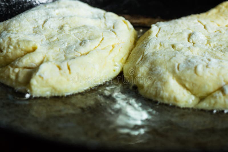 Kesostruvor eller pannkakor som steker, i att fräsa olja i den gamla järnensemblepannan, lantlig stil royaltyfri fotografi Kesostruvor eller pannkakor som steker, i att fräsa olja i den gamla järnensemblepannan, lantlig stil royaltyfri fotografi