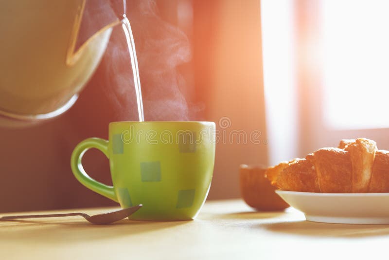 Kettle pouring boiling water into a cup