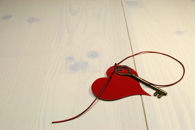 Key to My Heart  love concept, with gold heart shape key and red heart on white shabby chic wood table