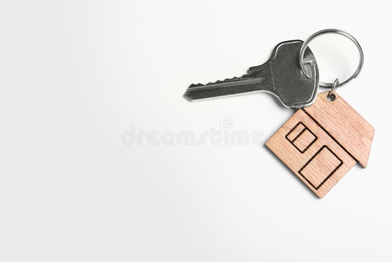 Key with trinket in shape of house isolated on white. Real estate agent services