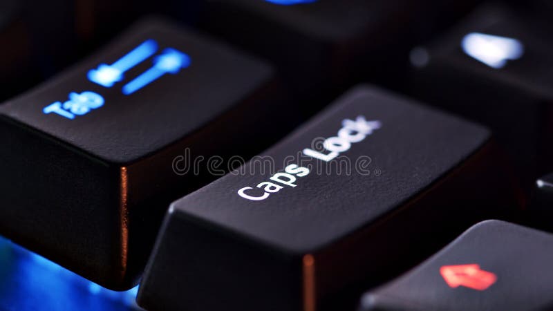 Keyboard key - Caps lock - macro shot. Modern gaming keyboard close-up with beautiful color backlight. Macro shooting of the rgb computer keyboard with backlight. Low angle view with soft focus