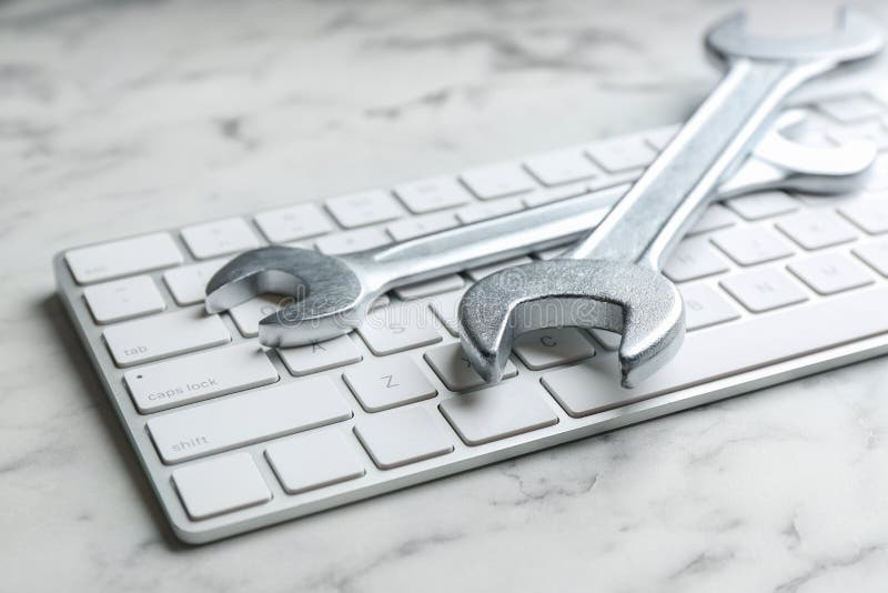 Keyboard and spanners on white marble table, closeup. Concept of technical support. Keyboard and spanners on white marble table, closeup. Concept of technical support