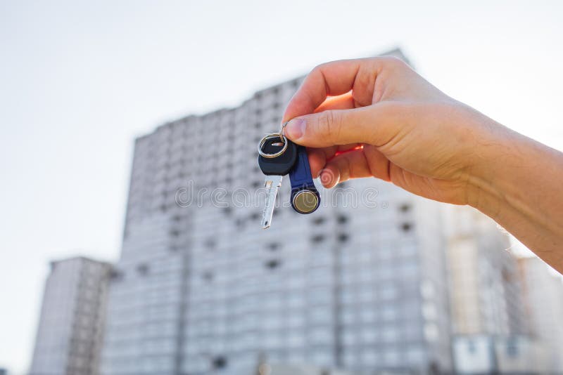 Key from an Apartment in a Man`s Hand on the Background of a New