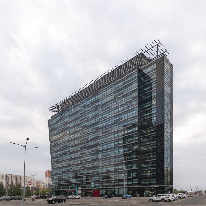 Khimki Business Park, diagonal cloudy view. Large glass office building with clouds in the background and parking