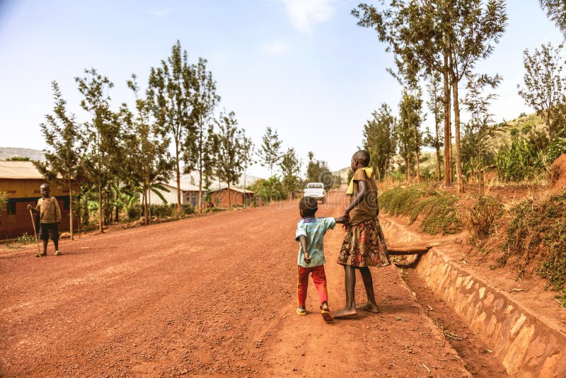 The car is going on dirt road and raising a cloud of dust. The African young girl is keeping her brotherâ€™s arm and tugging at his arm. The car is going on dirt road and raising a cloud of dust. The African young girl is keeping her brotherâ€™s arm and tugging at his arm.