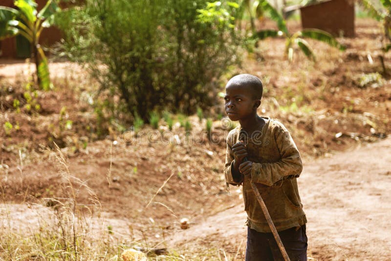 The farmer African child with his stick look across. He works in banana and coffee fields. There is a banana tree behind him. The farmer African child with his stick look across. He works in banana and coffee fields. There is a banana tree behind him.