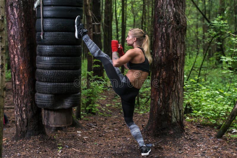 Kickboxing de pratique de femme exécutant un coup-de-pied de hache de jambe établissant dehors photographie stock Kickboxing de pratique de femme exécutant un coup-de-pied de hache de jambe établissant dehors photographie stock