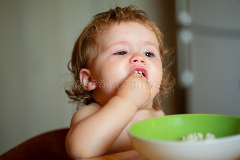 kid-baby-eat-soup-in-the-kitchen-with-dishes-and-spoon-stock-image