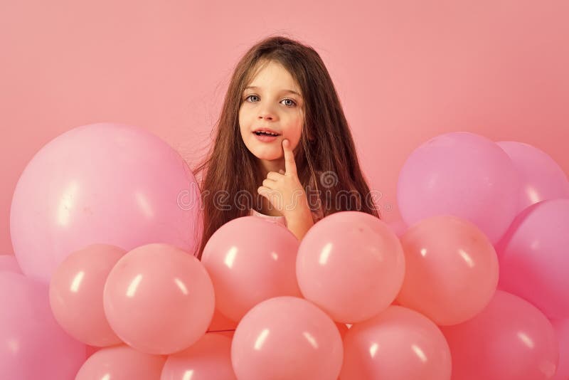 Kid in balloons, birthday. Little girl with long hair in pink balloons. Small girl child with party balloons, celebration. Beauty and fashion, punchy pastels. Birthday, happiness, childhood, look.