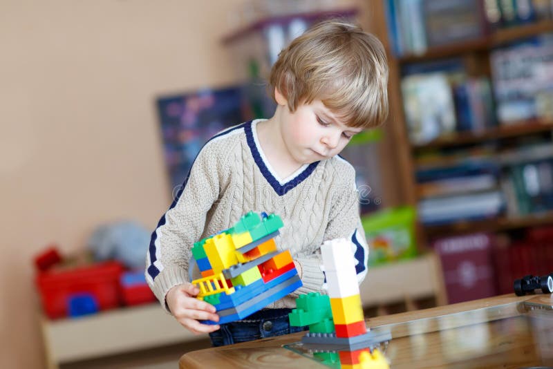 Kid boy playing with lots of colorful plastic blocks indoor stock images