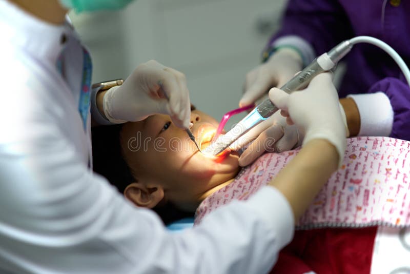 Kid is Cleaning Teeth Treatment by Dentist and Assistant Stock Photo