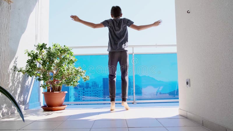 Kid doing sport exercises, running, jogging in place on the balcony. Sport, healthy lifestyle, active leisure. Stay home