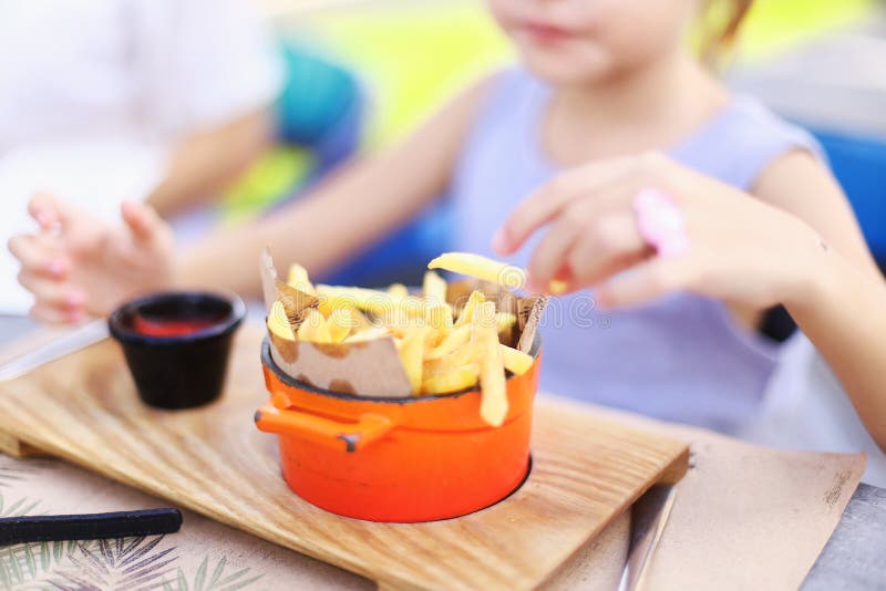 Kid eating fried potato, focus on French fries.