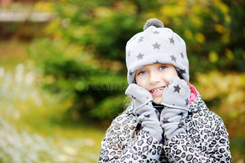 Kid girl has fun in garden with first snow