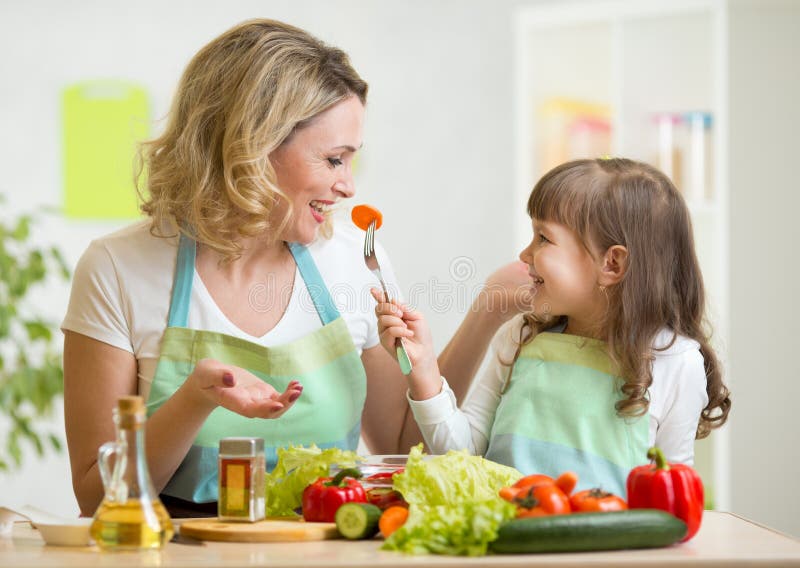 Kid girl and mother eating healthy food vegetables stock photos