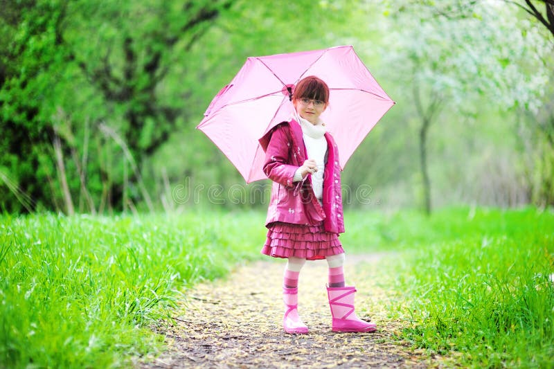 Kid girl posing outdoors with pink umbrella