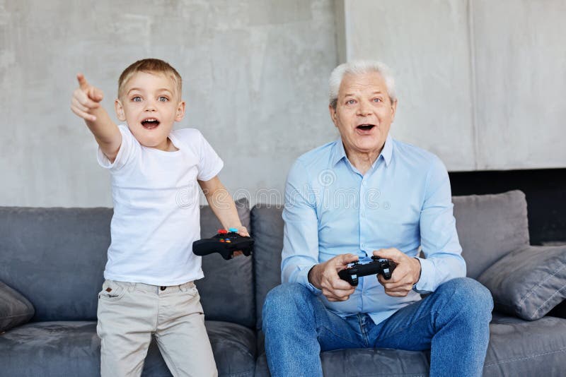 Kid and his grandpa playing video games together stock photos Kid and his grandpa playing video games together stock photos