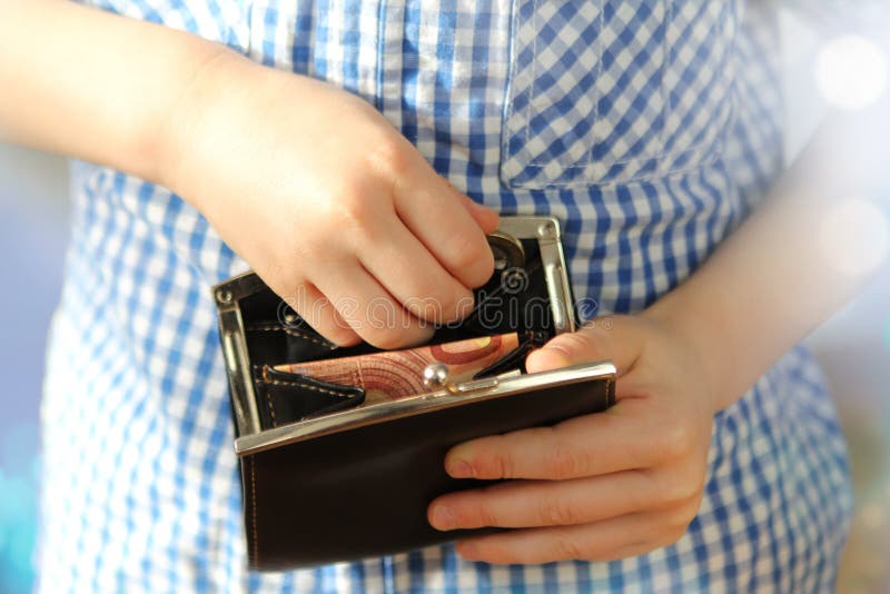 Kid holds a wallet with euro banknotes and looks with his fingers there, the concept of pocket money, theft, shopping