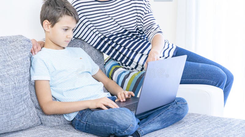 Kid learning online with laptop computer at home. Mother help him, explains task. Technology, online learning, distance. Kid learning online with laptop computer royalty free stock photos Kid learning online with laptop computer at home. Mother help him, explains task. Technology, online learning, distance. Kid learning online with laptop computer royalty free stock photos