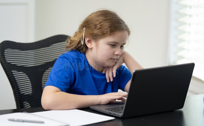 Kid learning while using laptop for school homework. Student learning at home desk with laptop. Boy learning with laptop for royalty free stock photography