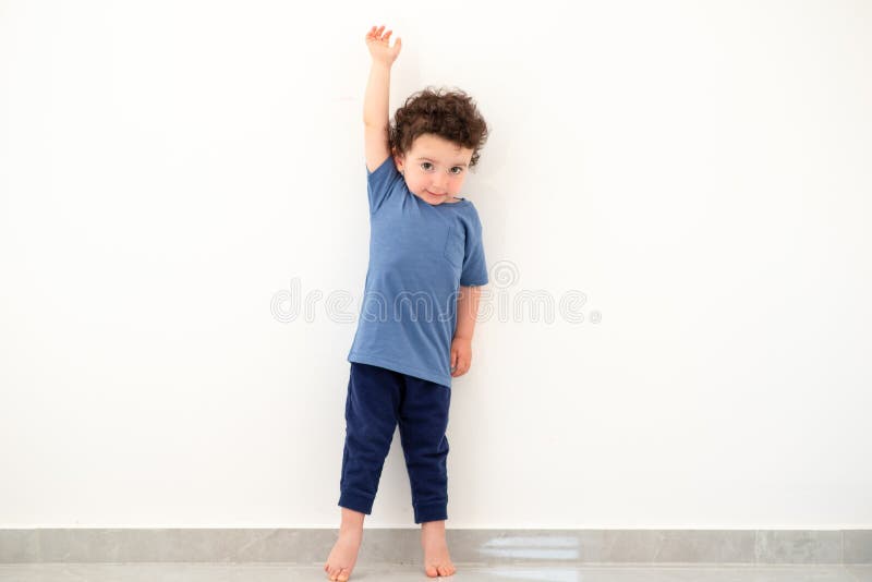 Height of child grow up. Little boy measuring his height on white