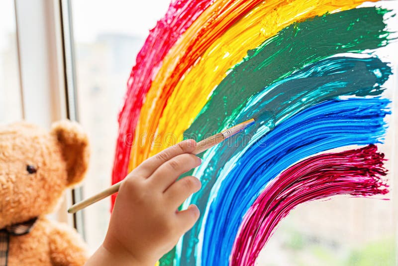 Kid painting rainbow during Covid-19 quarantine at home. Girl near window. Stay at home Social media campaign for coronavirus royalty free stock photo Kid painting rainbow during Covid-19 quarantine at home. Girl near window. Stay at home Social media campaign for coronavirus royalty free stock photo