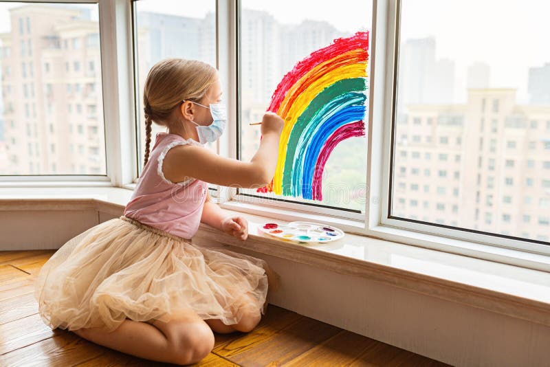 Kid painting rainbow during Covid-19 quarantine at home. Girl near window. Stay at home Social media campaign for coronavirus royalty free stock photo Kid painting rainbow during Covid-19 quarantine at home. Girl near window. Stay at home Social media campaign for coronavirus royalty free stock photo