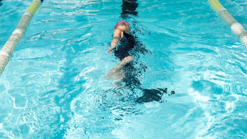 Kid practice to swim backstroke in swimming class in the swimming pool stock photo Kid practice to swim backstroke in swimming class in the swimming pool stock photo
