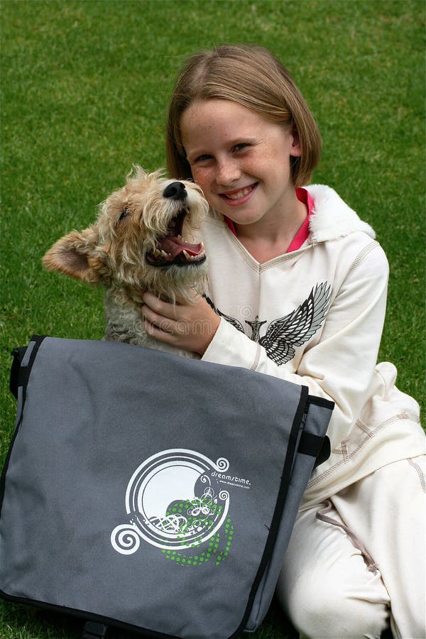 A white caucasian girl child and her puppy playing outdoors with dreamstime messenger bag with a happy expression on her face. A white caucasian girl child and her puppy playing outdoors with dreamstime messenger bag with a happy expression on her face