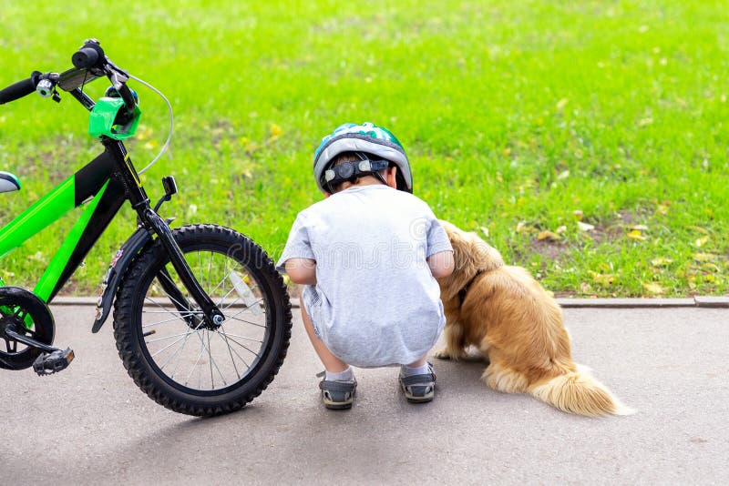 Kid riding bicycle in city park and stopped to meet cute little dog. Child having fun playing with pet friend outdoors. Children royalty free stock photo Kid riding bicycle in city park and stopped to meet cute little dog. Child having fun playing with pet friend outdoors. Children royalty free stock photo