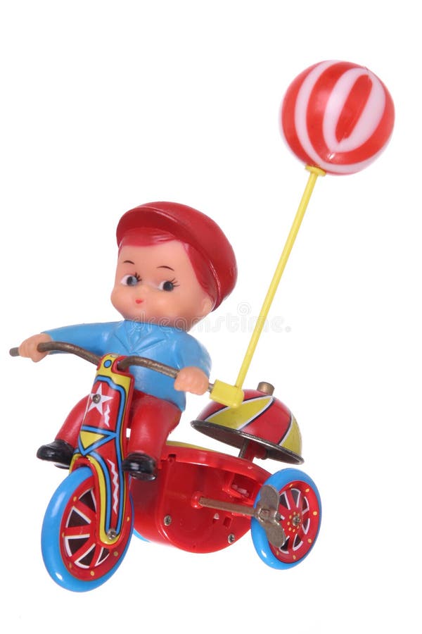 Little plastic boy, holding a balloon, riding a tin trike, with a bell on the back, isolated against white ground. Little plastic boy, holding a balloon, riding a tin trike, with a bell on the back, isolated against white ground