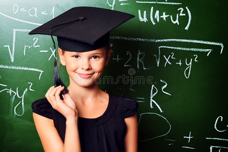 Portrait of a cute schoolgirl in academic hat and big round spectacles at a classroom. Portrait of a cute schoolgirl in academic hat and big round spectacles at a classroom.