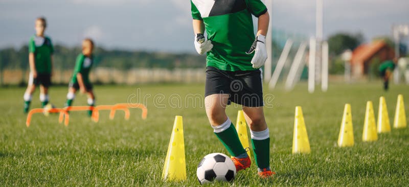 kid soccer player dribbling cones boy uniform practice ball child kicking grass young athlete improving 213465772