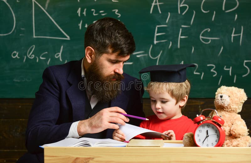 Kid Studies Individually With Teacher, At Home. Teacher And Pupil In Mortarboard, Chalkboard On Background. Father With