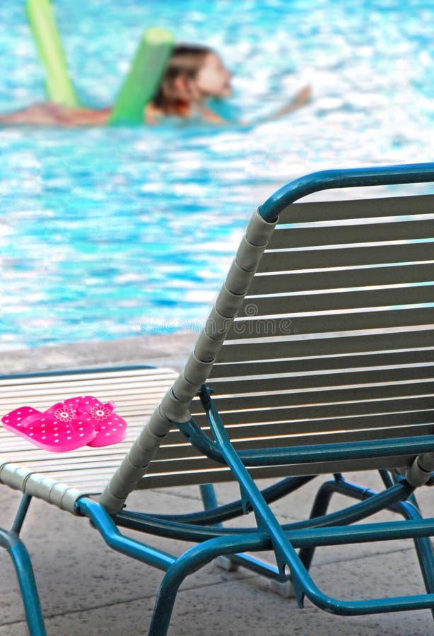 Young girl swimming in pool with lounge chair at poolside. Young girl swimming in pool with lounge chair at poolside